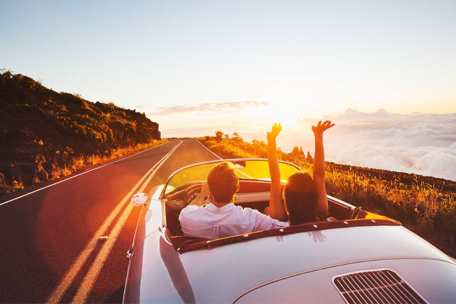 Couple driving at sunset in a convertible