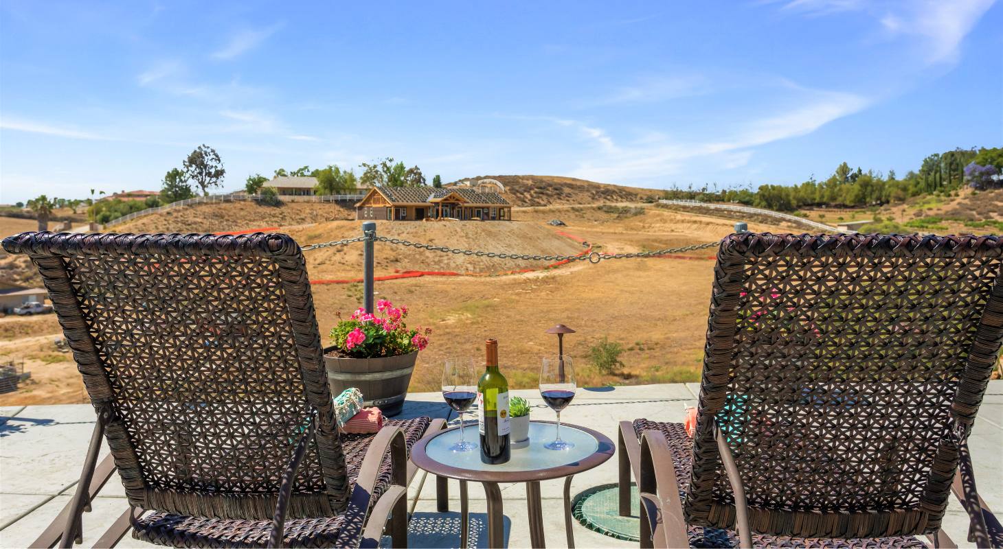 Chairs and glasses of wine facing a beautiful vineyard at Temecula Inns